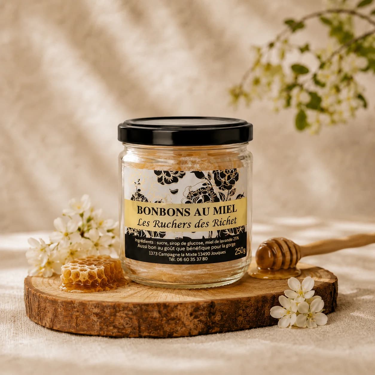 Bocal de bonbons au miel Les Ruchers des Richet sur une rondelle de bois, avec un rayon de miel et une cuillère à miel